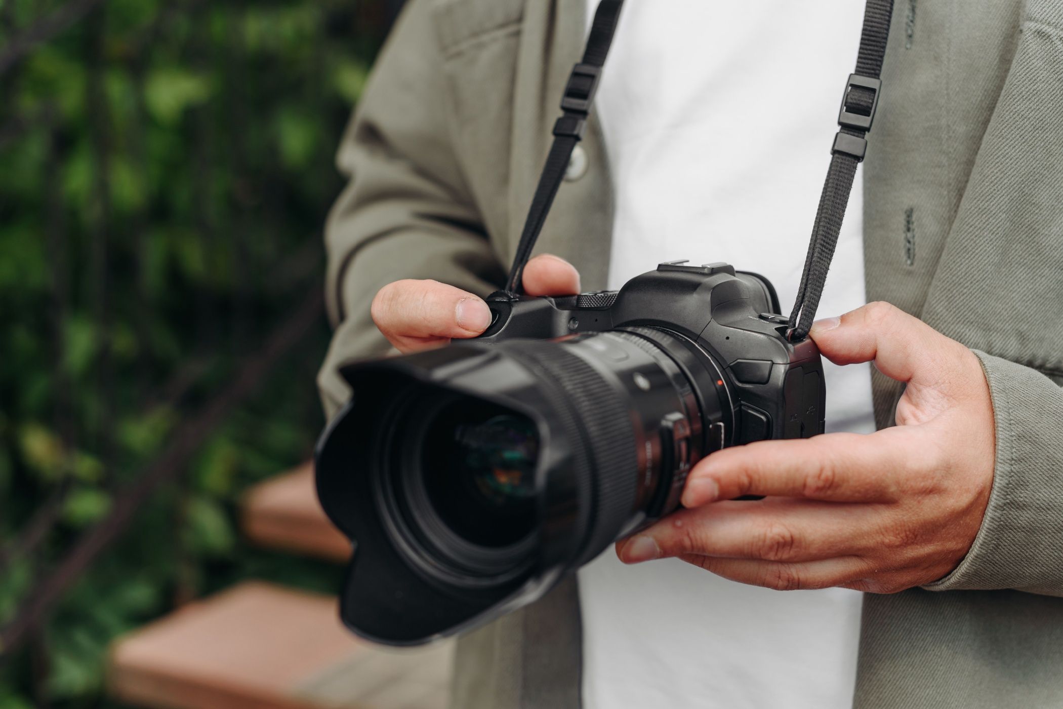 عکاس جوان بزرگسال در تی شرت سفید که دوربین DSLR را در دست دارد