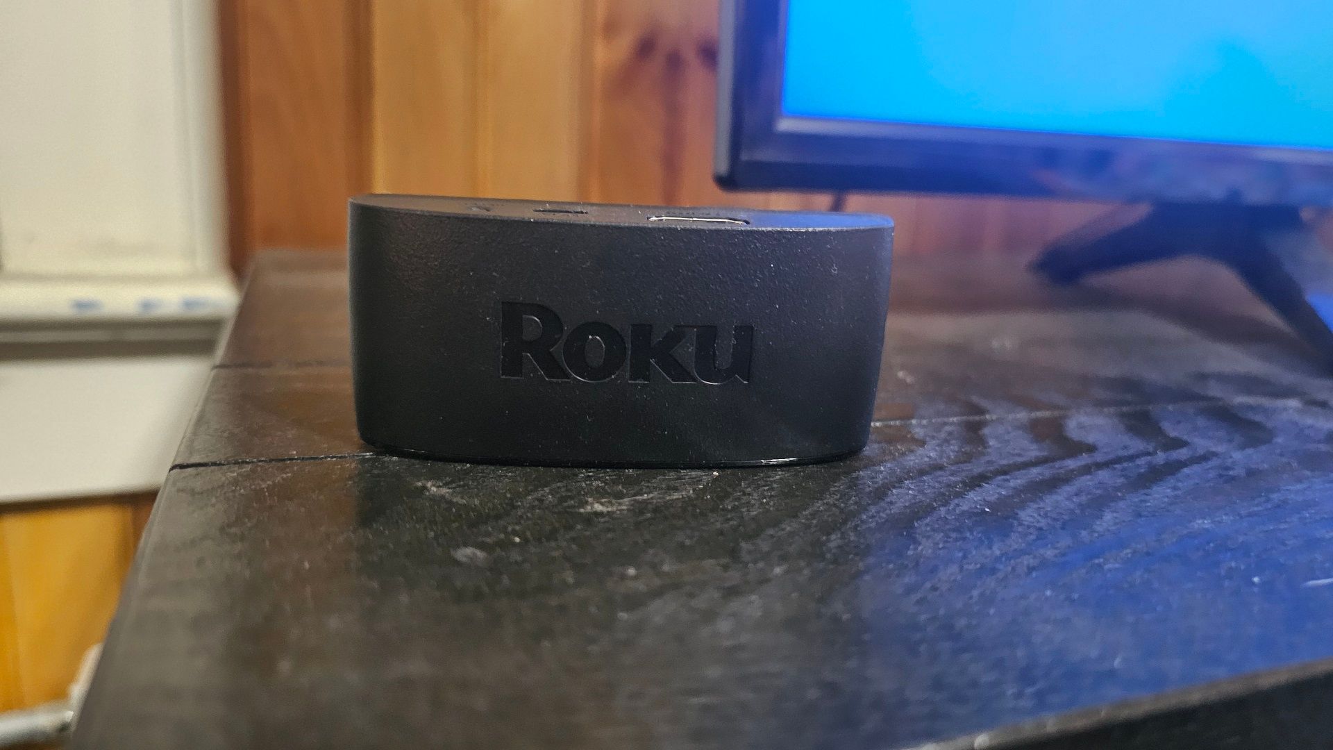یک دستگاه پخش Roku در بالای یک غرفه تلویزیون ، در کنار تلویزیون.