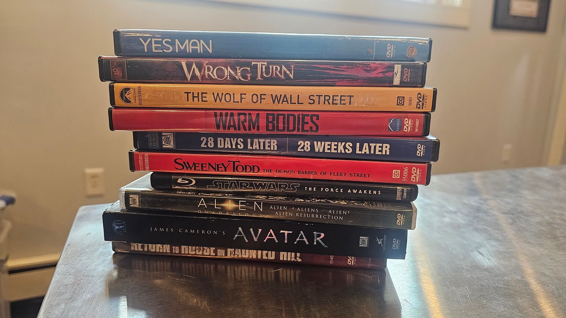 پشته DVD و Blu-rays ، روی یک میز فلزی نقره ای.