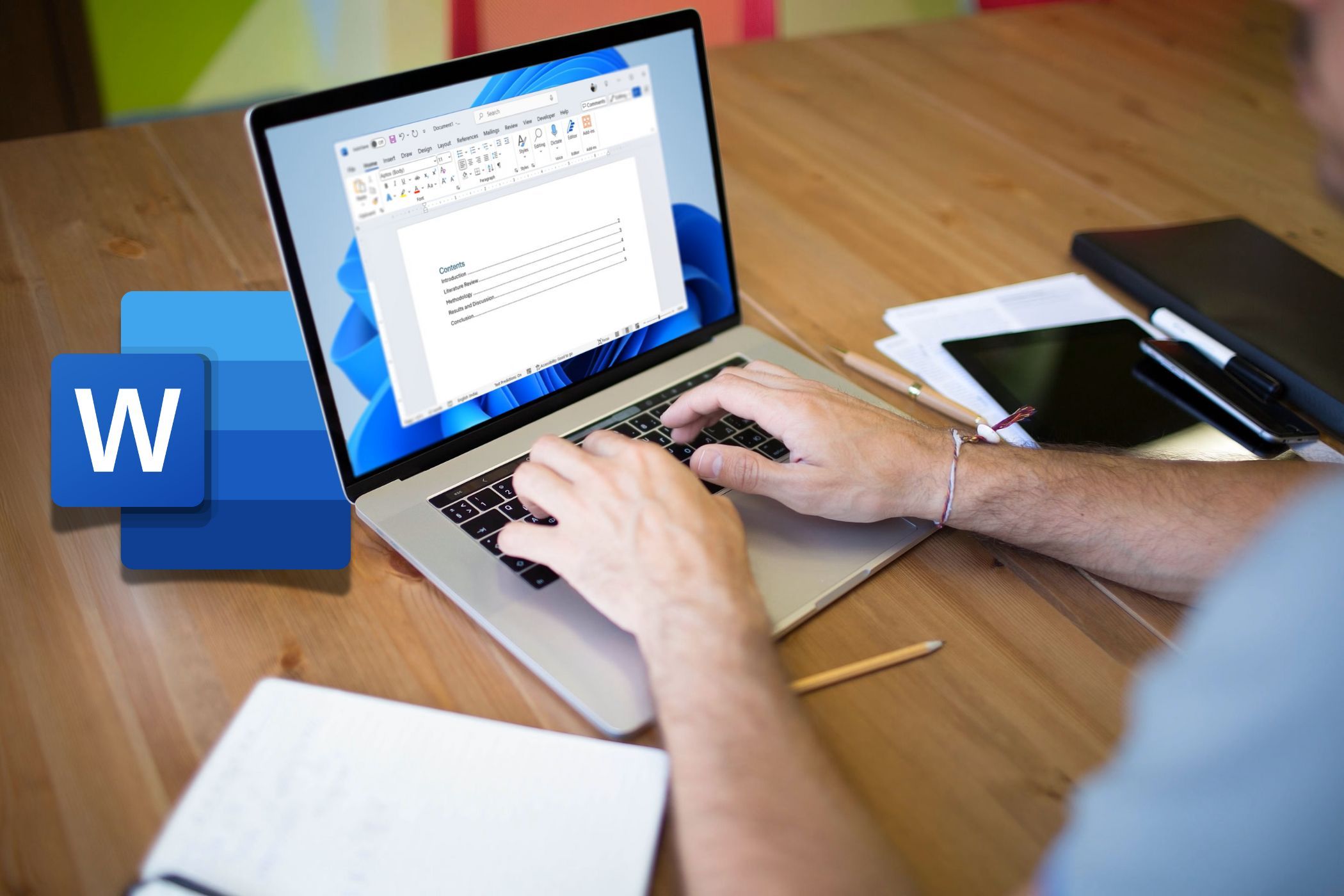 شخصی که از لپ تاپ Microsoft Word روی میز با نماد Word در سمت چپ استفاده می کند