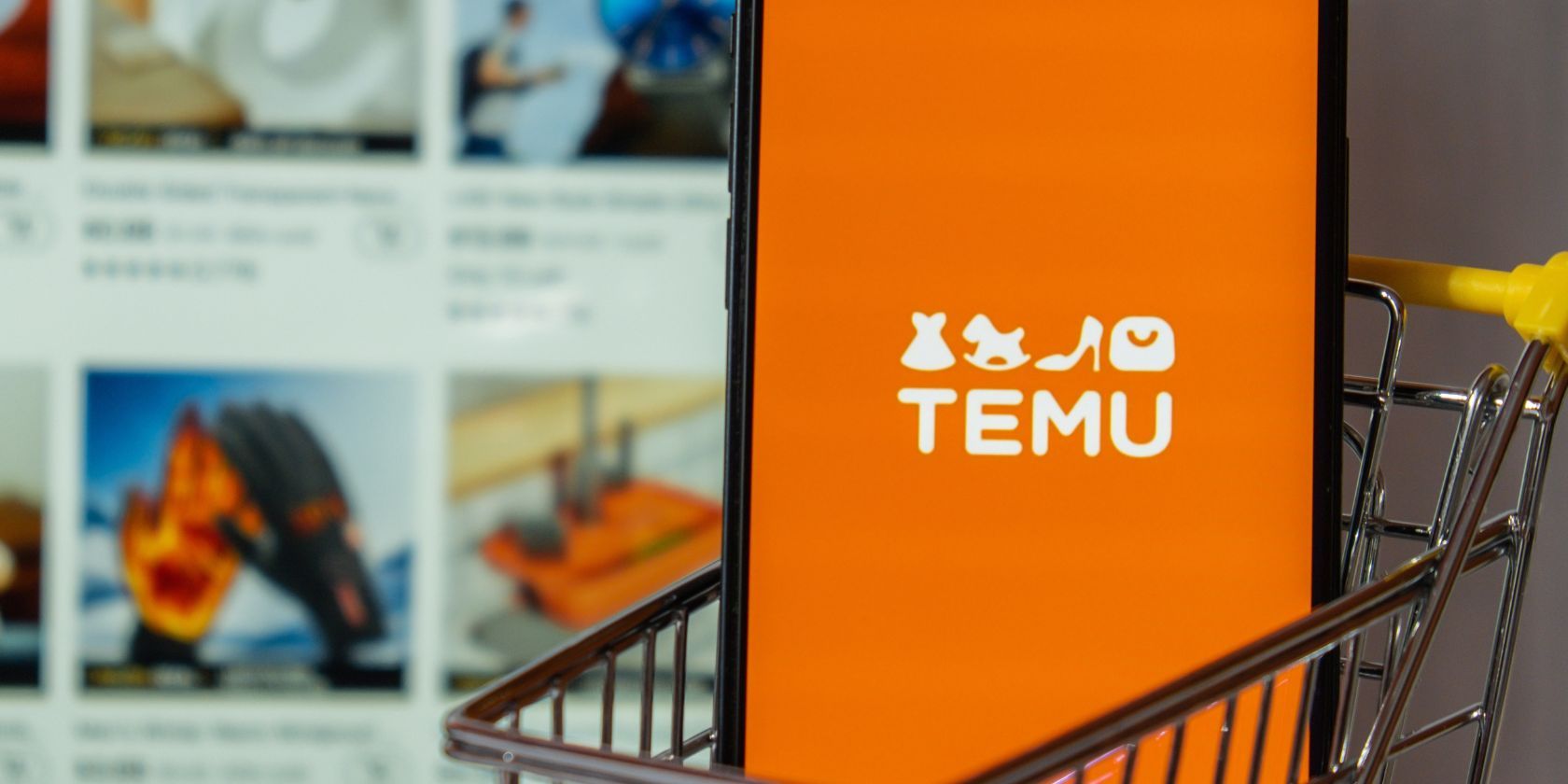 برنامه TEMU در تلفن های هوشمند نشسته در چرخ دستی در مقابل لپ تاپ