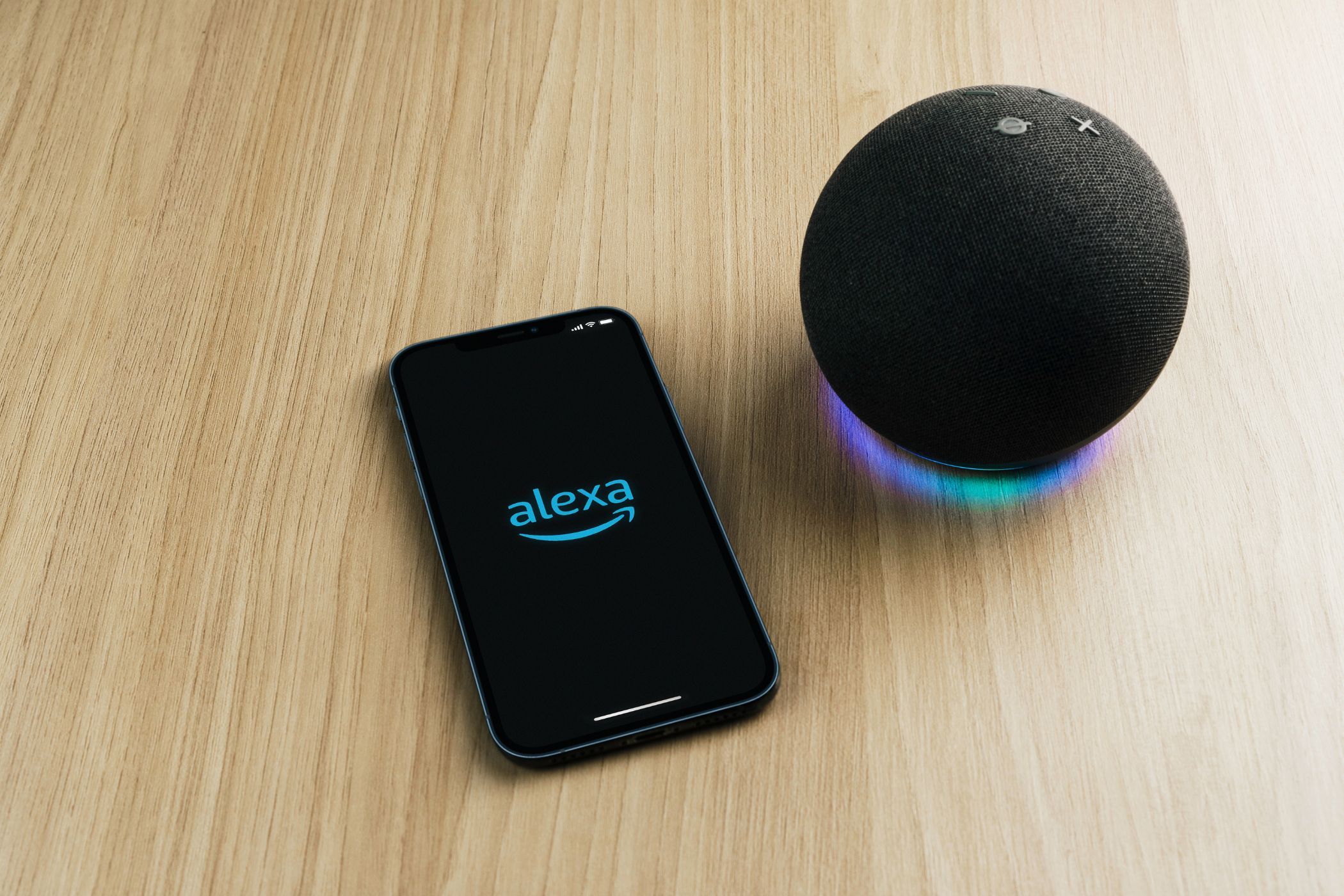 برنامه Alexa در یک تلفن هوشمند روی یک میز کنار یک بلندگو اکو