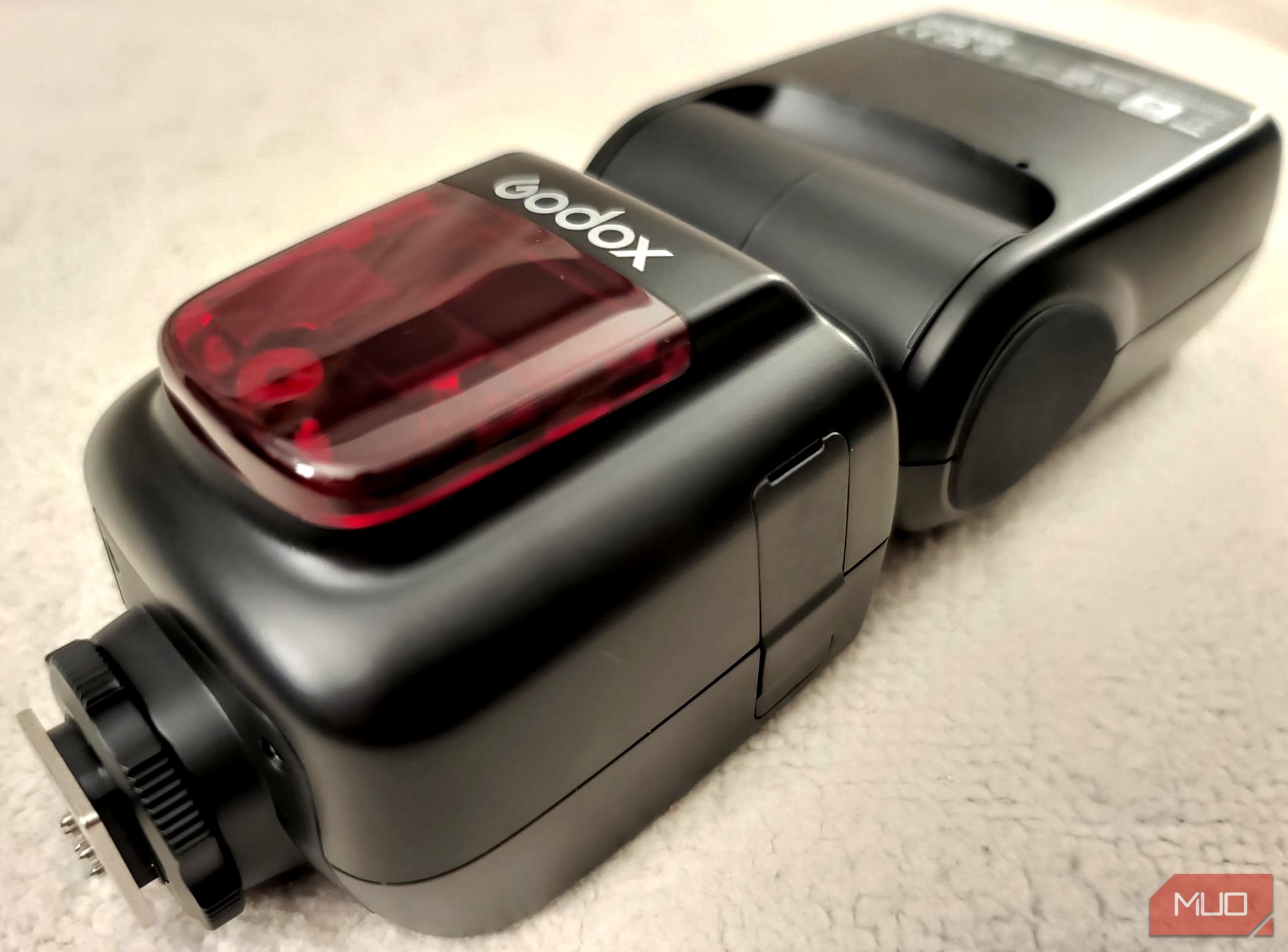 یک فلش دوربین خارجی Godox V860II-C که روی یک پتو بژ گذاشته شده است