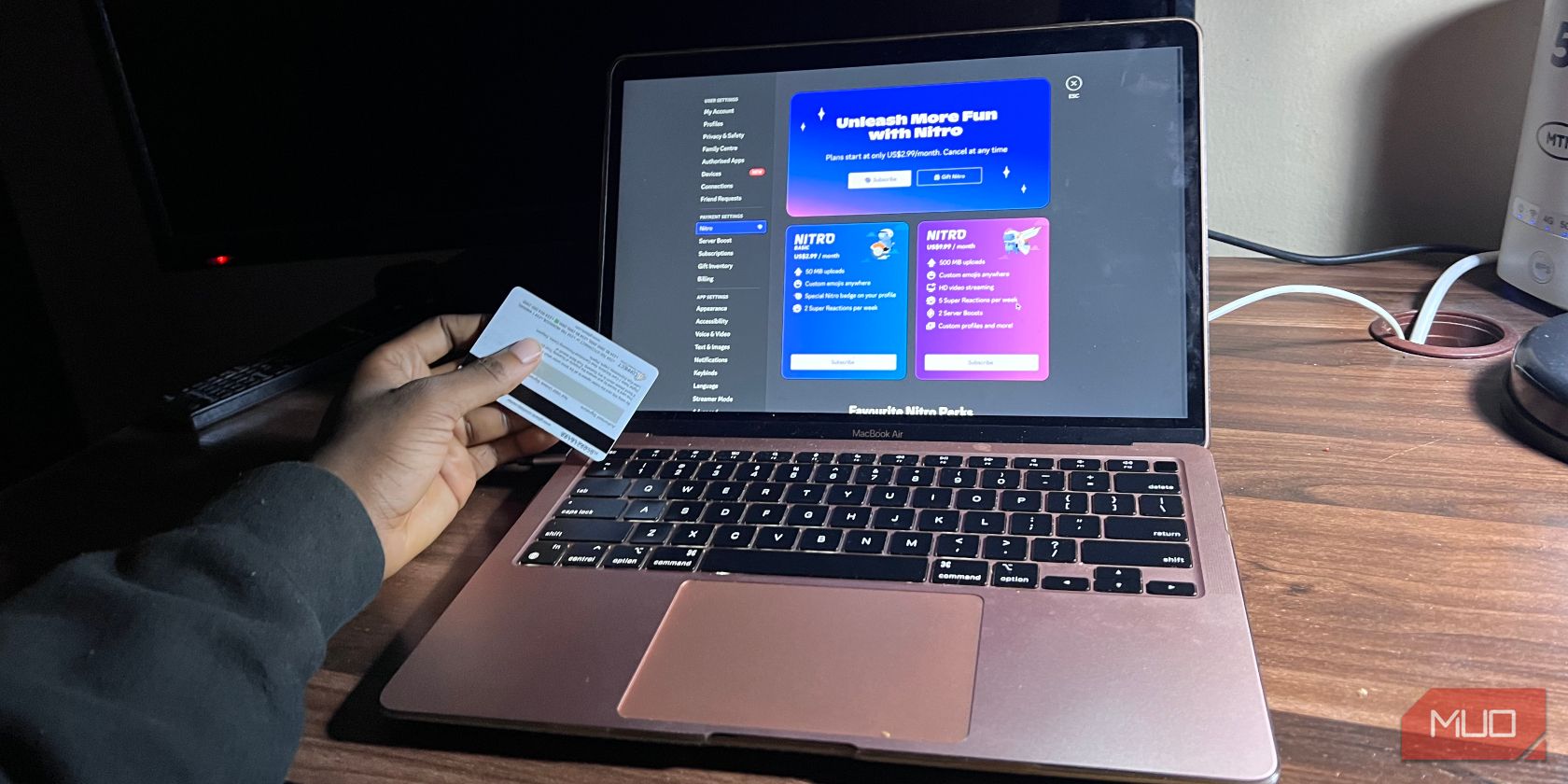 مردی که دارای کارت با جزئیات نیترو Discord در صفحه Air Macbook است