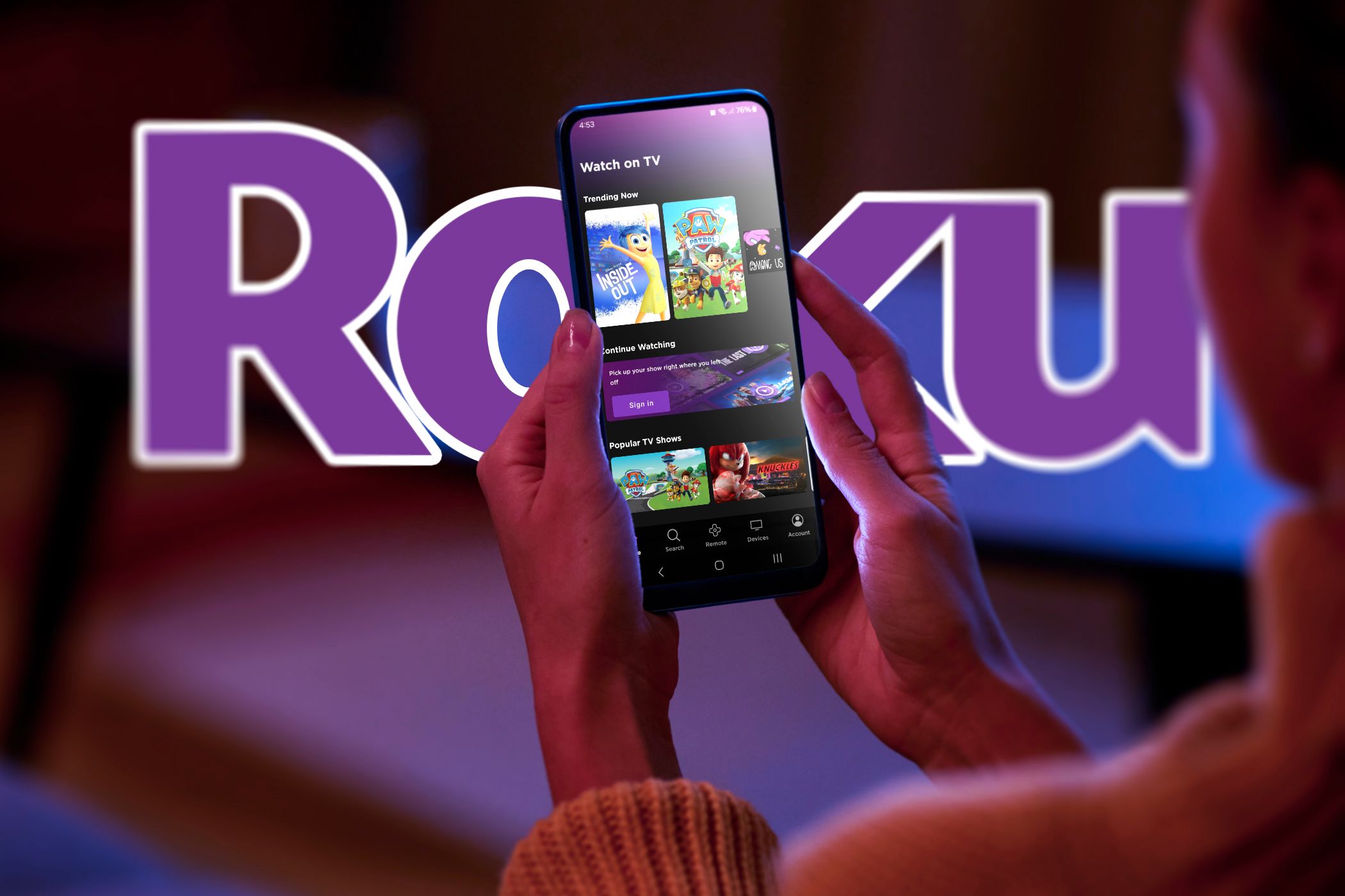 زنی با برنامه Roku در تلفن هوشمند خود و آرم Roku در پس زمینه.