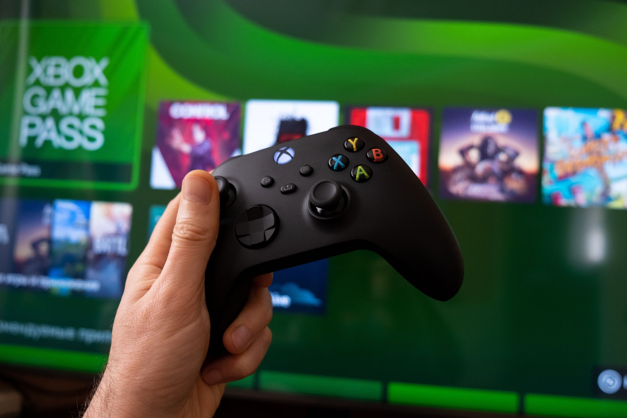 یک کنترلر Xbox با Xbox Game در پس زمینه از روی صفحه عبور می کند