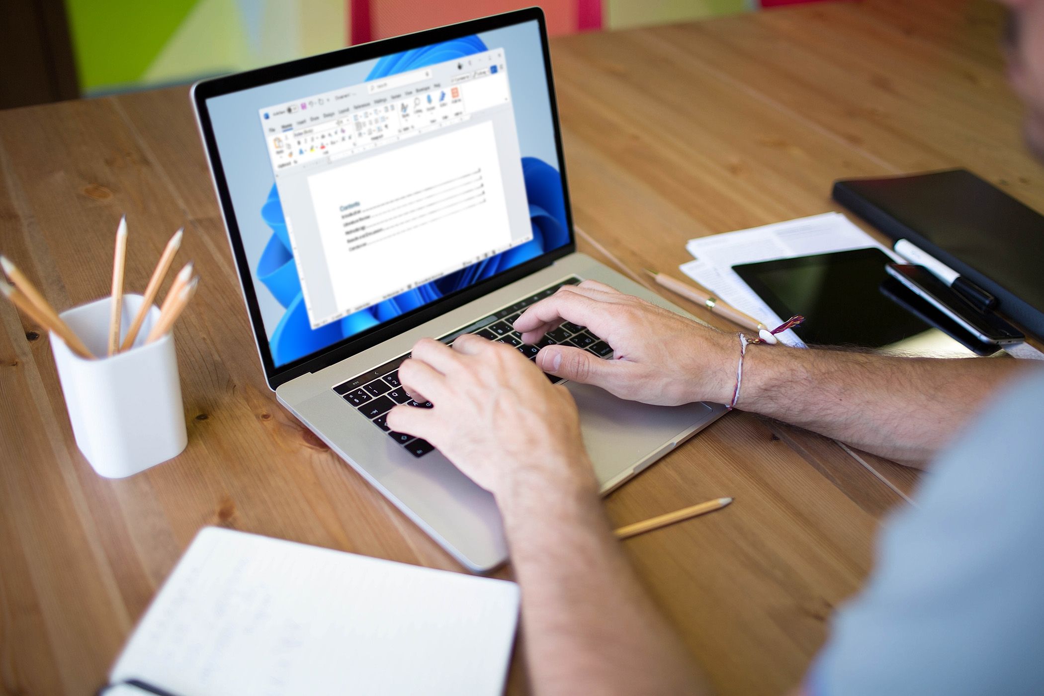 شخصی که از لپ تاپ استفاده می کند تا یک فهرست از مطالب را در Microsoft Word تهیه کند