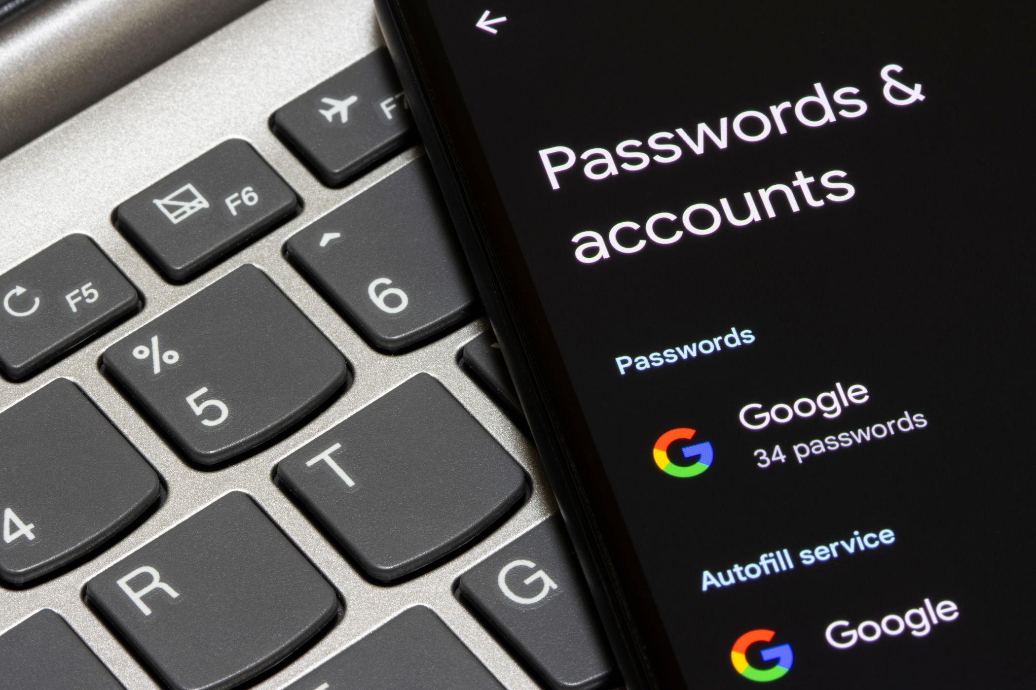 حساب و رمز عبور Google در صفحه تلفن هوشمند کنار لپ تاپ