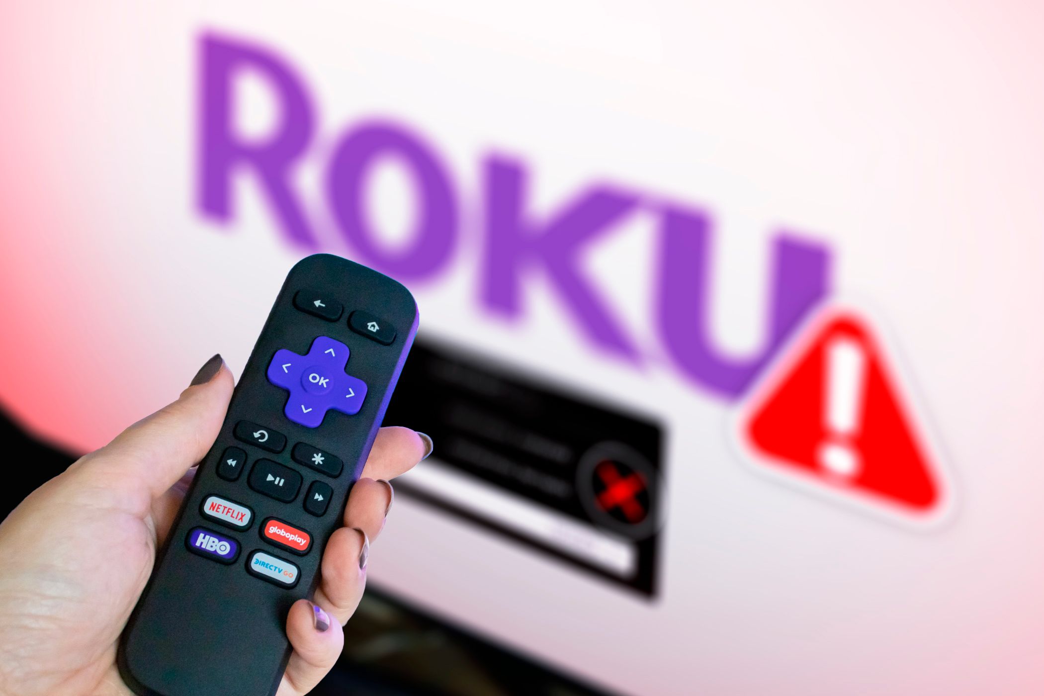 دستی که یک ریموت Roku را با یک تلویزیون در پس زمینه که نشان می دهد آرم Roku تار و هشدار را نشان می دهد.