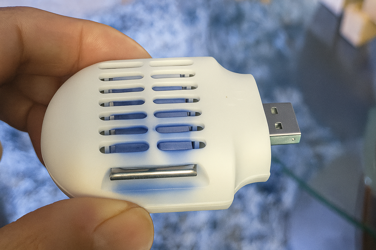 دستی که دارای یک دفع پشه کوچک ، سفید و با قدرت USB است.