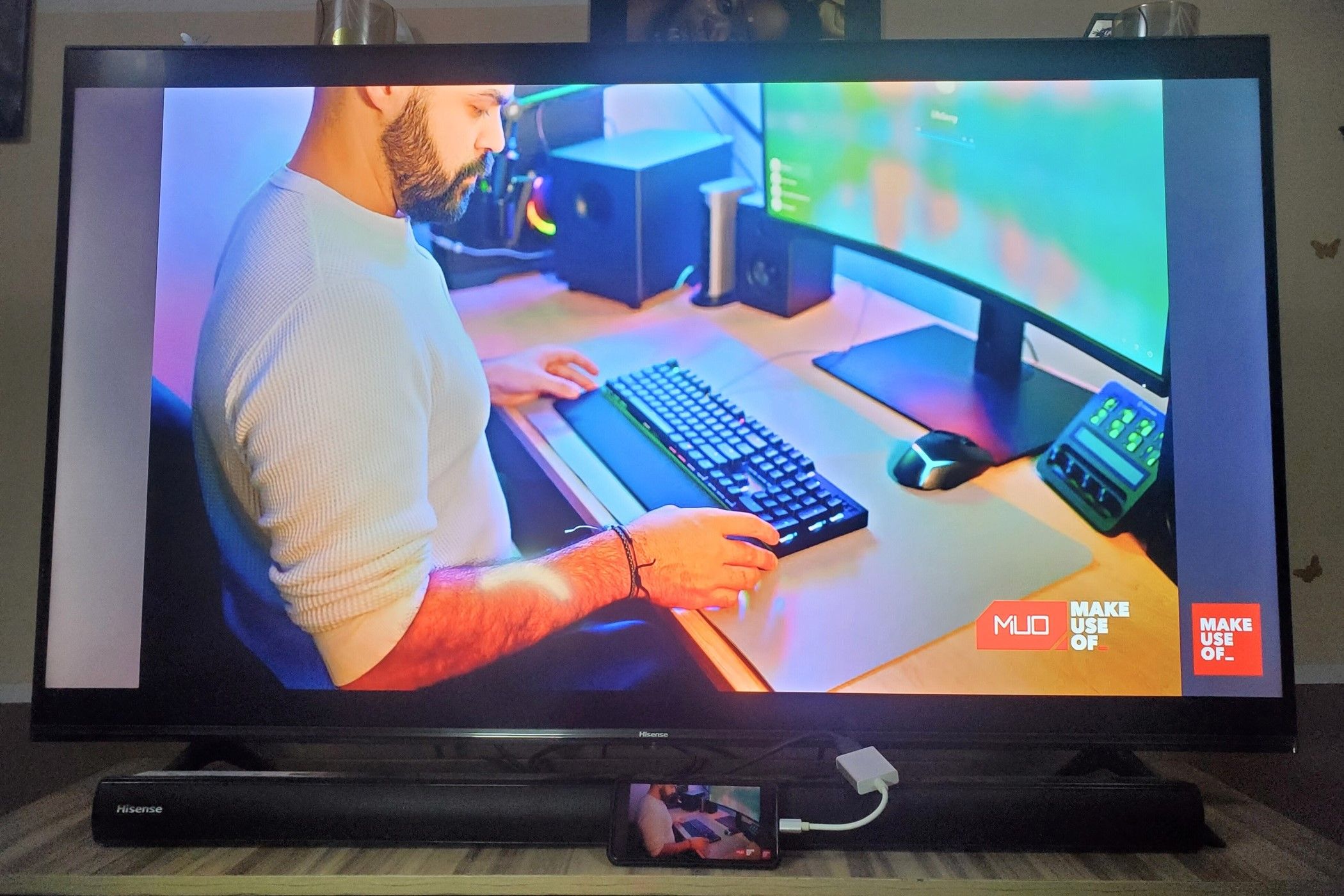 یک تلفن هوشمند متصل به تلویزیون از طریق USB-C به HDMI آداپتور آینه ای از صفحه نمایش آن و نمایش یک مرد با استفاده از صفحه کلید 2