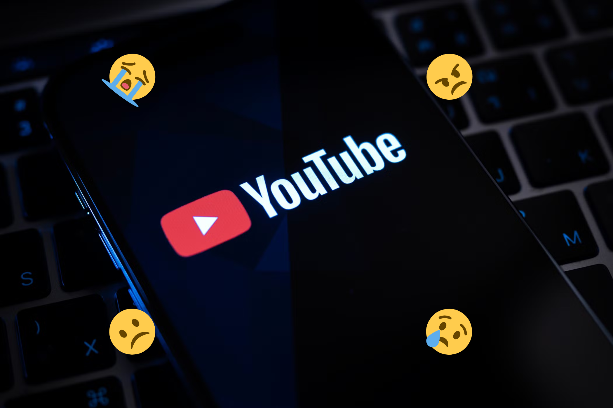یک تلفن هوشمند که آرم YouTube را روی صفحه نمایش می دهد ، که توسط چهره های ایموجی غمگین و عصبانی احاطه شده است