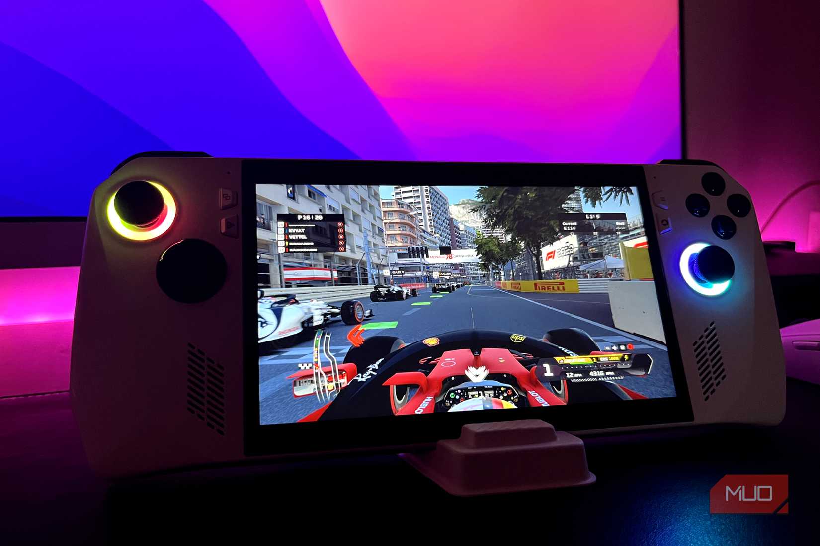 Asus Rog Ally در یک پایه با مانیتور در پس زمینه