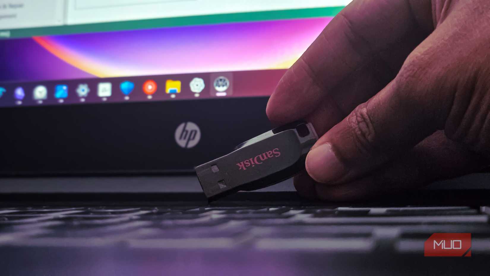 دست انسانی که درایو USB Sandisk را روی صفحه کلید لپ تاپ نگه داشته است