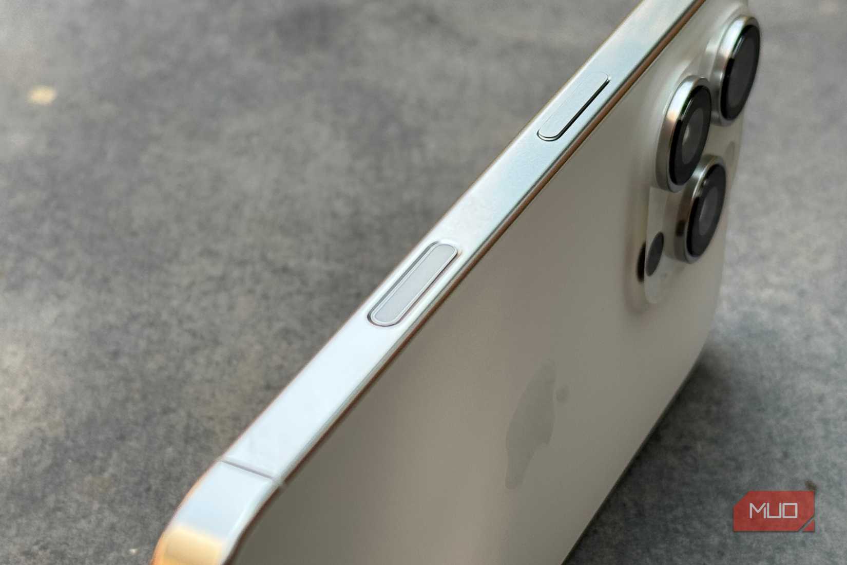 iPhone 16 Pro با تمرکز روی لبه سمت راست خود با دکمه کنترل دوربین روی یک دال سنگی نگه داشته شد