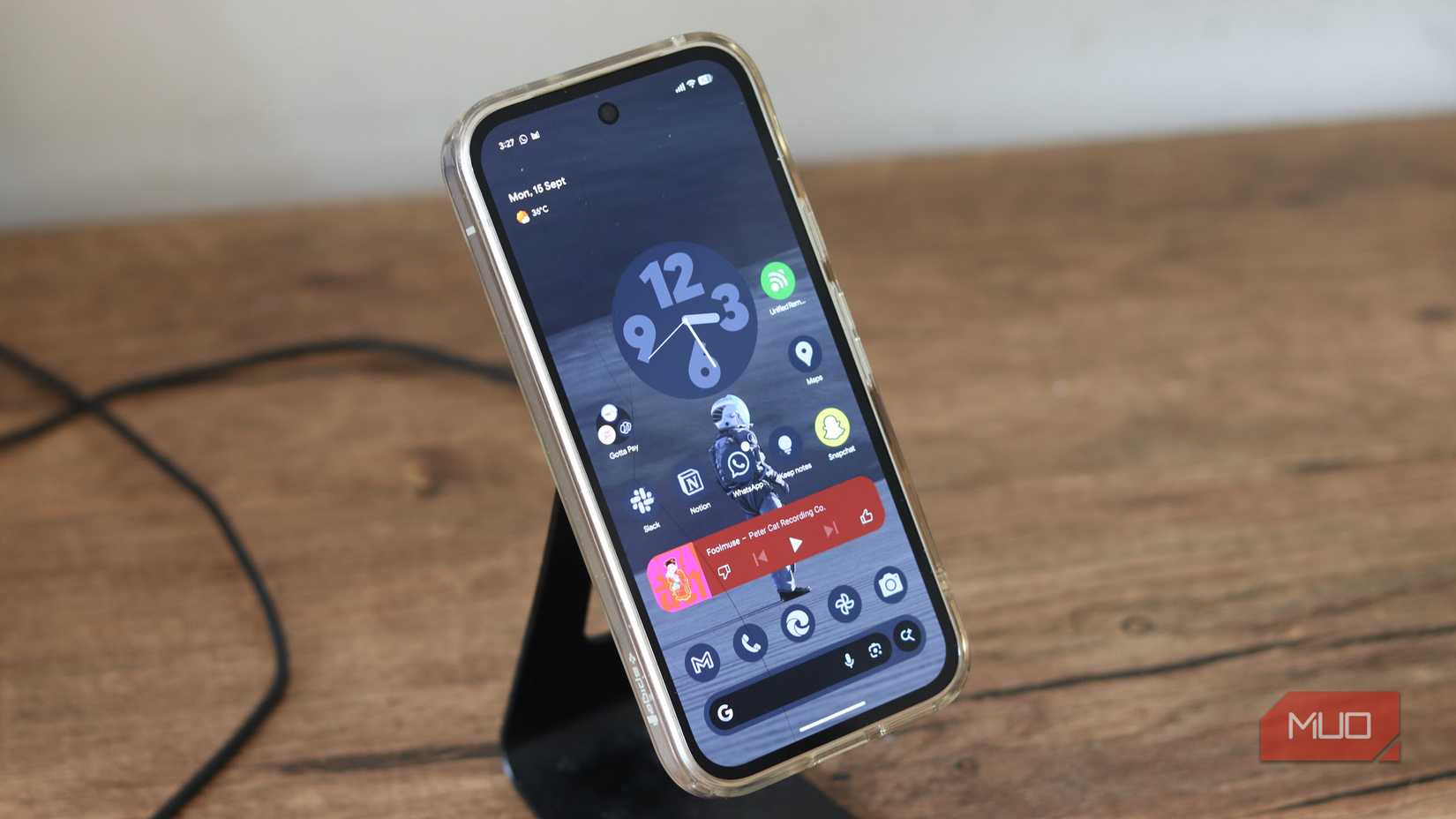 Pixel 9a در یک پایه شارژ بی سیم.
