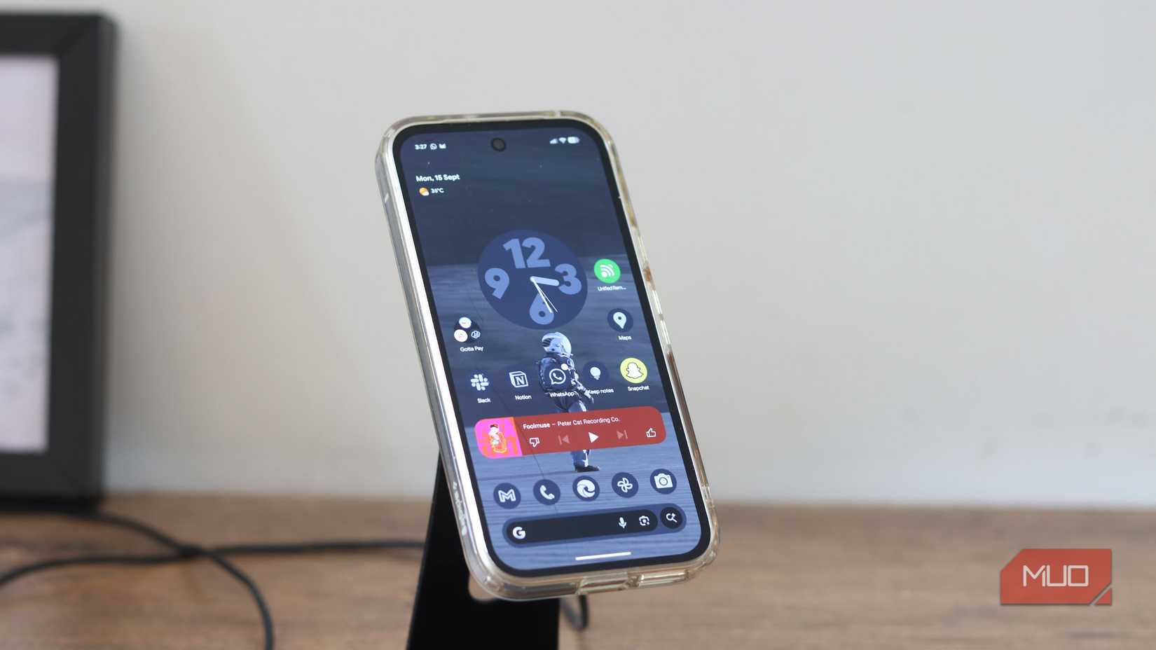 Pixel 9a در یک پایه شارژ بی سیم.