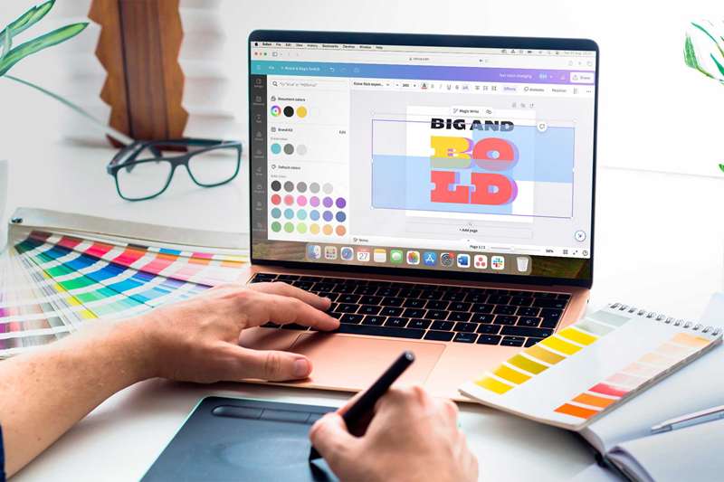 یک لپ‌تاپ با Canva باز روی یک میز همراه با برخی ابزارهای طراحی