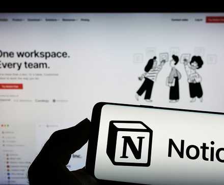 یک تلفن همراه و مانیتوری که رابط کاربری Notion و لوگوی آن را نمایش می‌دهد