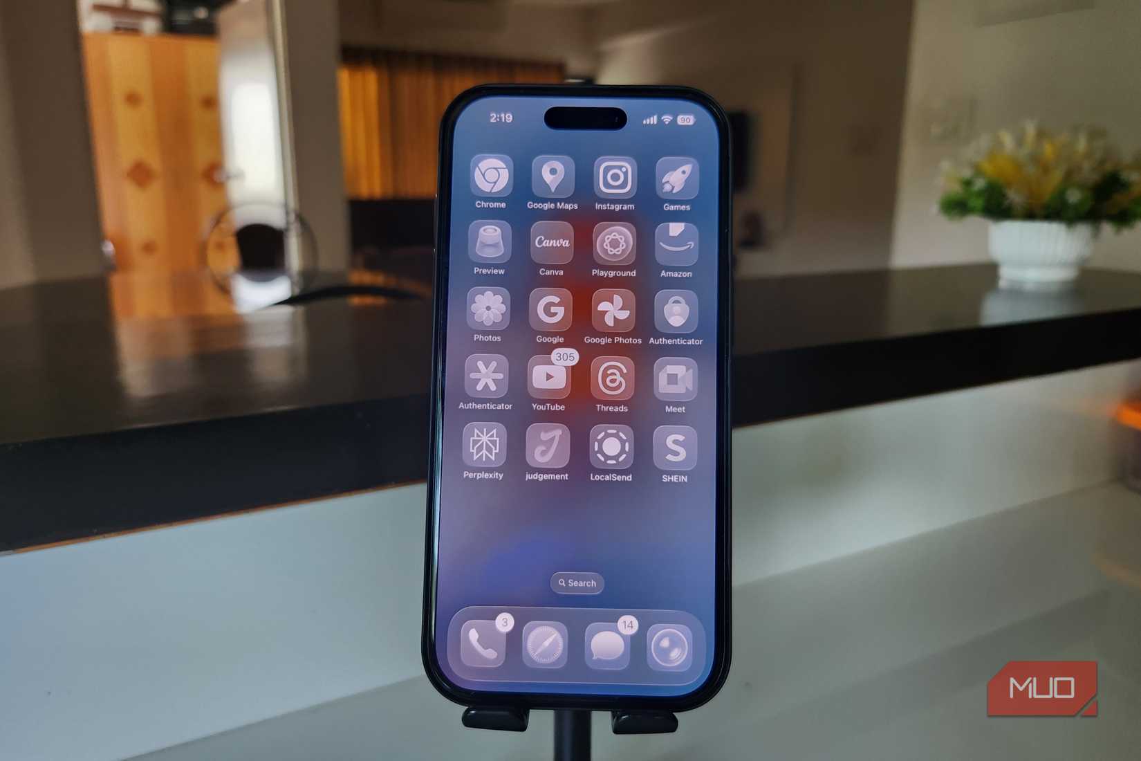 iPhone 16 Pro نشان دادن صفحه اصلی iOS 26 روی یک پایه