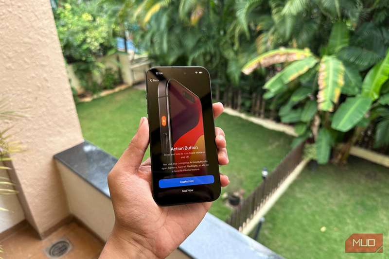 iPhone 15 Pro در دست یک مرد که صفحه نمایش ویژگی دکمه Action را نشان می‌دهد