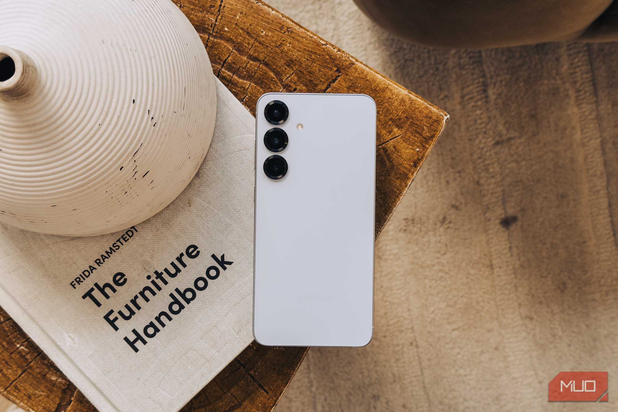 Galaxy S25 سامسونگ در رنگ نقره‌ای روی یک کتاب سفید