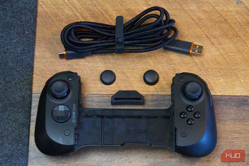 کنترلر Scuf Nomad با لوازم جانبی بر روی میز قهوه‌ای همراه پد نمدی خاکستری