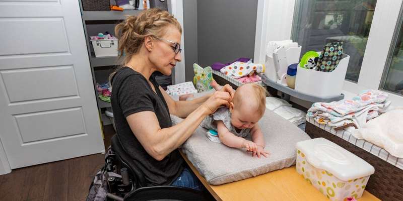 مادر در صندلی چرخ‌دار پس از تعویض پوشک نوزادش در اتاق‌نوزادک.