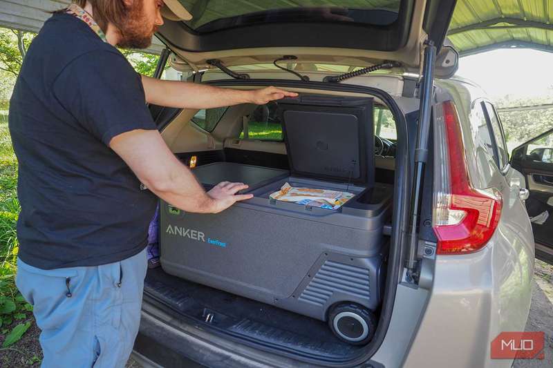 مردی که کنار SUV ایستاده و دست‌هایش روی کولر