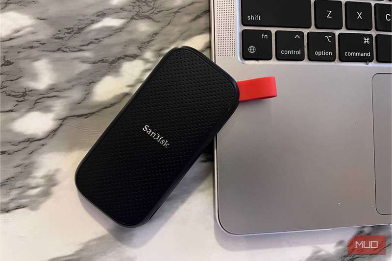 یک SSD ساندیسک قرار گرفته در کنار یک مکبوک