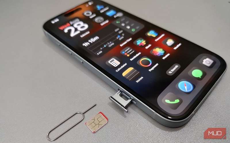 یک iPhone 15 با سینی سیم و ابزار خروج سیم روی یک میز