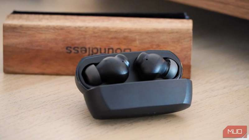 ایربادهای Belkin SoundForm Rhythm ANC در جلوی یک برس تمیزکننده رکورد.