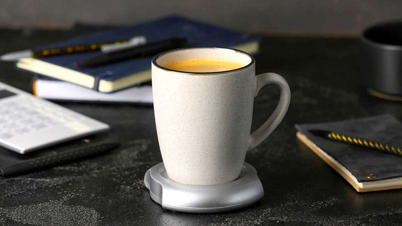 فنجان قهوه روی گرم‌کن قهوه روی میز