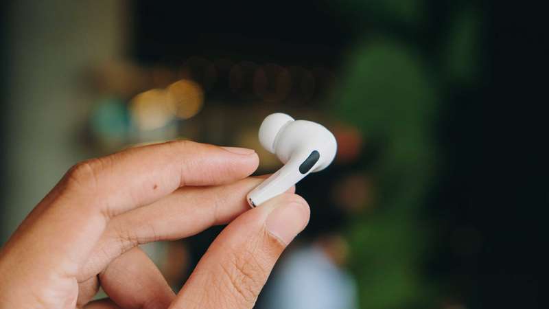 انگشتان در حال نگه داشتن یک گوش‌دست AirPod