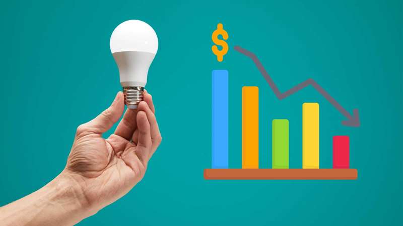 دست در حال نگه داشتن لامپ LED بر روی پس‌زمینه فیروزه‌ای با نمودار نزولی