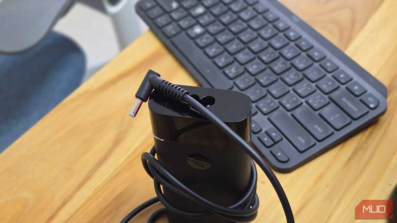 شارژر لپ‌تاپ HP با کابل پیچیده شده دور آن