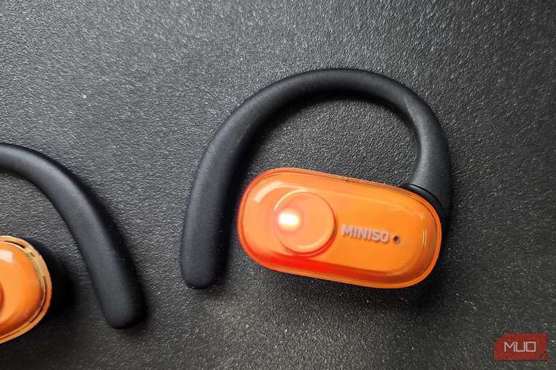 یکی از هدفون‌های مینوسو M185 که بیرون از کیس هستند، با نور نشان‌دهنده که روشن هستند