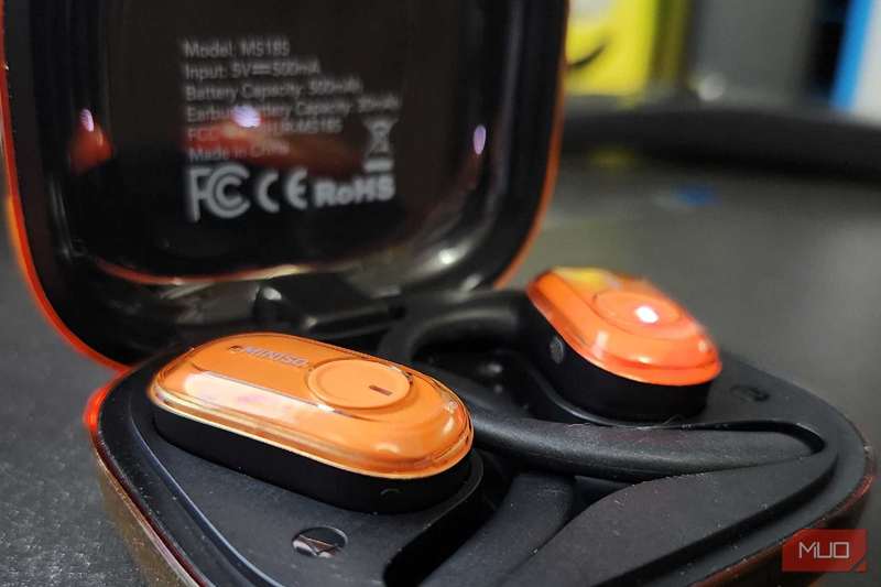 مینوسو MS185 داخل کیس شارژ که دکمه کنترل لمسی کوچک را نشان می‌دهد