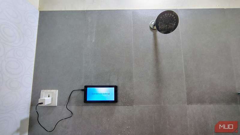 تبلت قدیمی که با پدهای چسبی بر روی دیوار حمام چسبیده است.