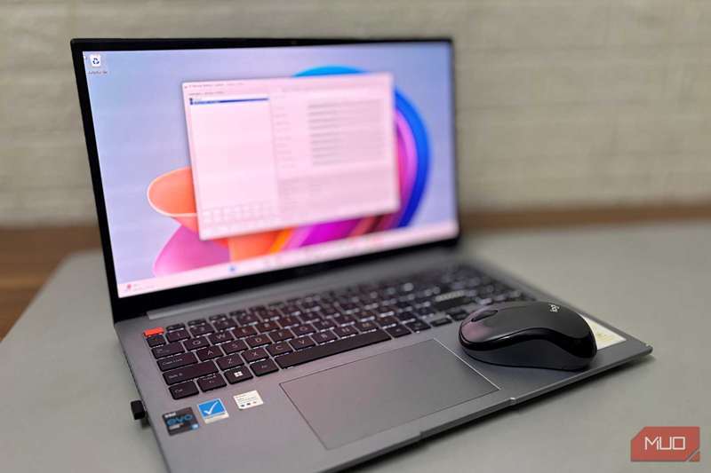 لپ‌تاپ باز با صفحهٔ تار شده که X-Mouse Button Control را اجرا می‌کند و یک ماوس بی‌سیم Logitech در کنار آن روی میز قرار دارد