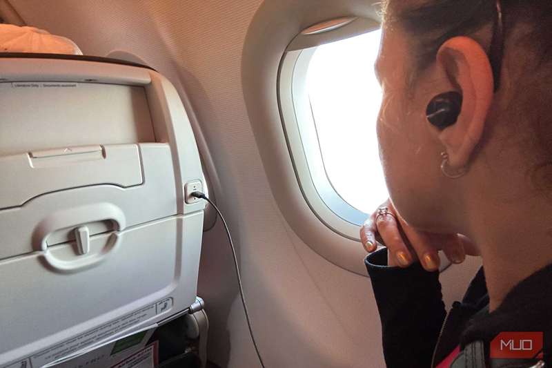 زنکی که از پنجرهٔ یک هواپیما نگاه می‌کند و هدفون‌های پاناسونیک تکنیکز EAH‑AZ100 را بر گوش دارد.