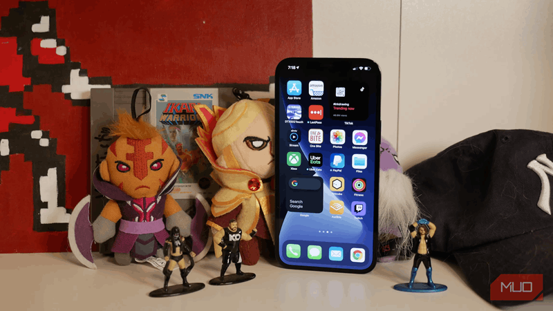 آیفون ۱۲ پرو مکس با اسباب‌بازی‌ها روی قفسه، نمای جلویی