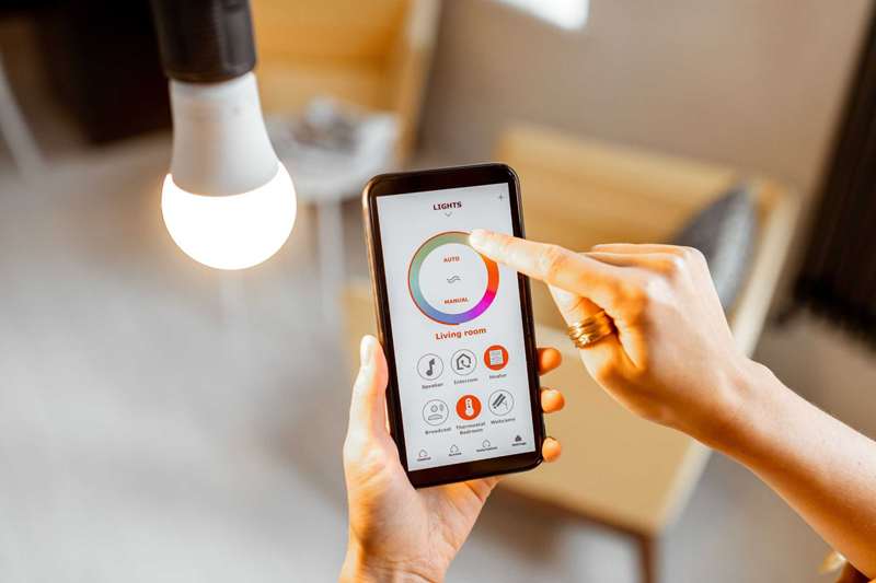 فردی که از یک برنامه برای تغییر رنگ‌ها روی یک لامپ هوشمند استفاده می‌کند