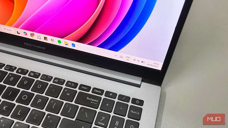 لپ‌تاپ ASUS Vivobook که دسکتاپ ویندوز 11 را با نوار وظیفه و پس‌زمینهٔ رنگی نشان می‌دهد