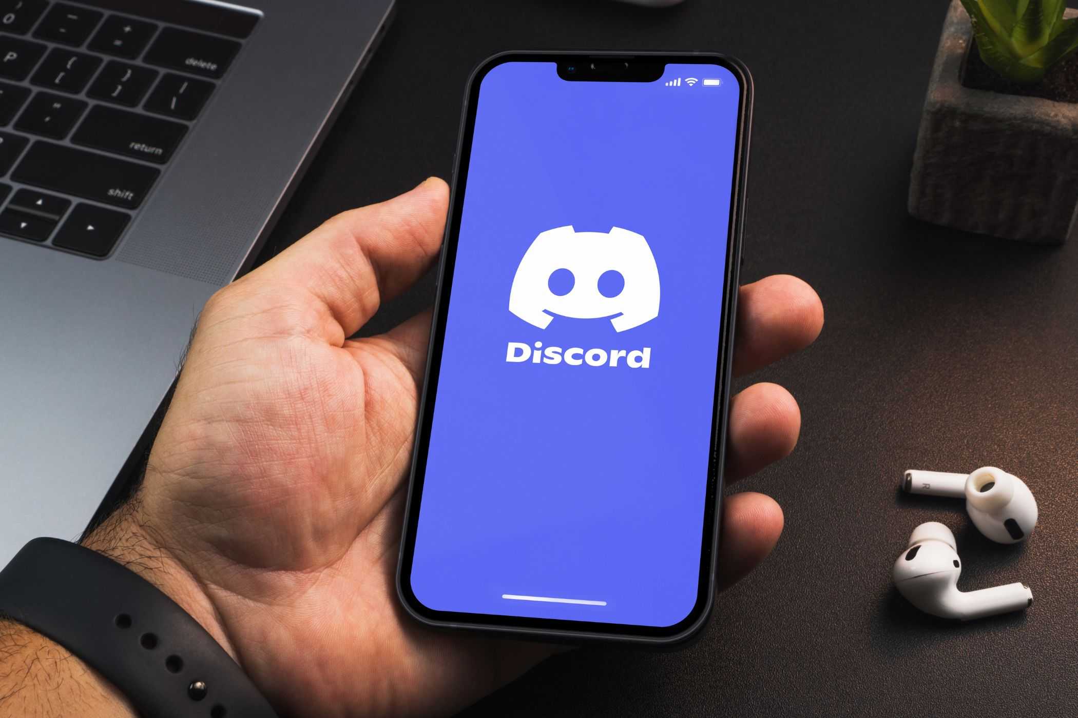 مردی که یک گوشی هوشمند با برنامه Discord در دست دارد