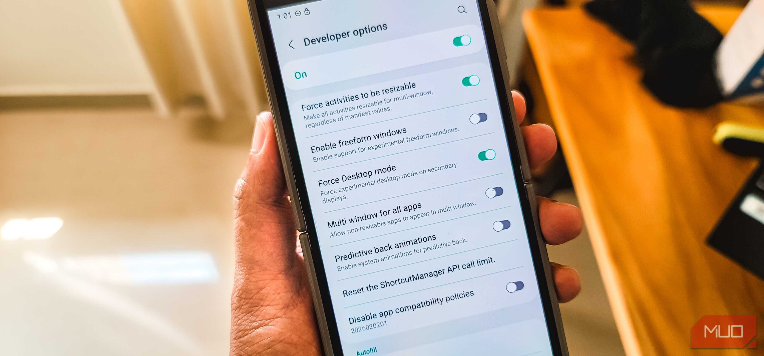 شخصی که یک Galaxy Z Flip 6 را در دست دارد و صفحه گزینه‌های توسعه‌دهنده باز است