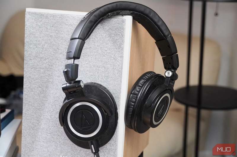 هدفون‌های ATH-M50x از Audio Technica روی یک بلندگو تکیه کرده‌اند.