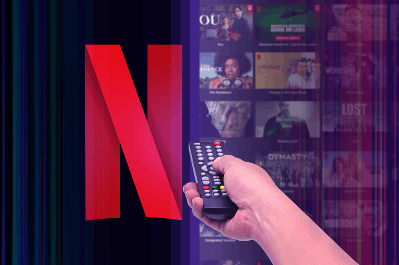 دست نگه‌دارنده یک ریموت کنترل که به لوگوی نتفلیکس اشاره دارد، با چندین برنامه که در پس‌زمینه تار شده‌اند
