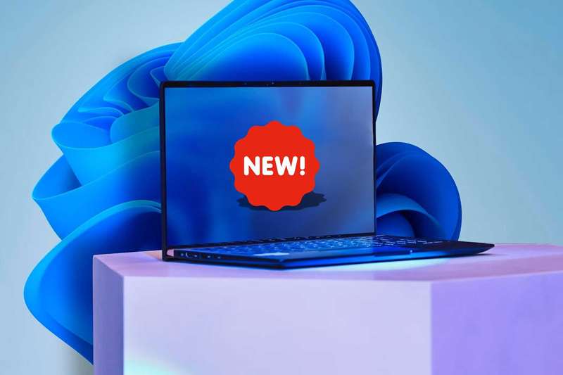 یک لپ‌تاپ با برچسب NEW روی صفحه‌نمایش و تصویر پس‌زمینه ویندوز 11
