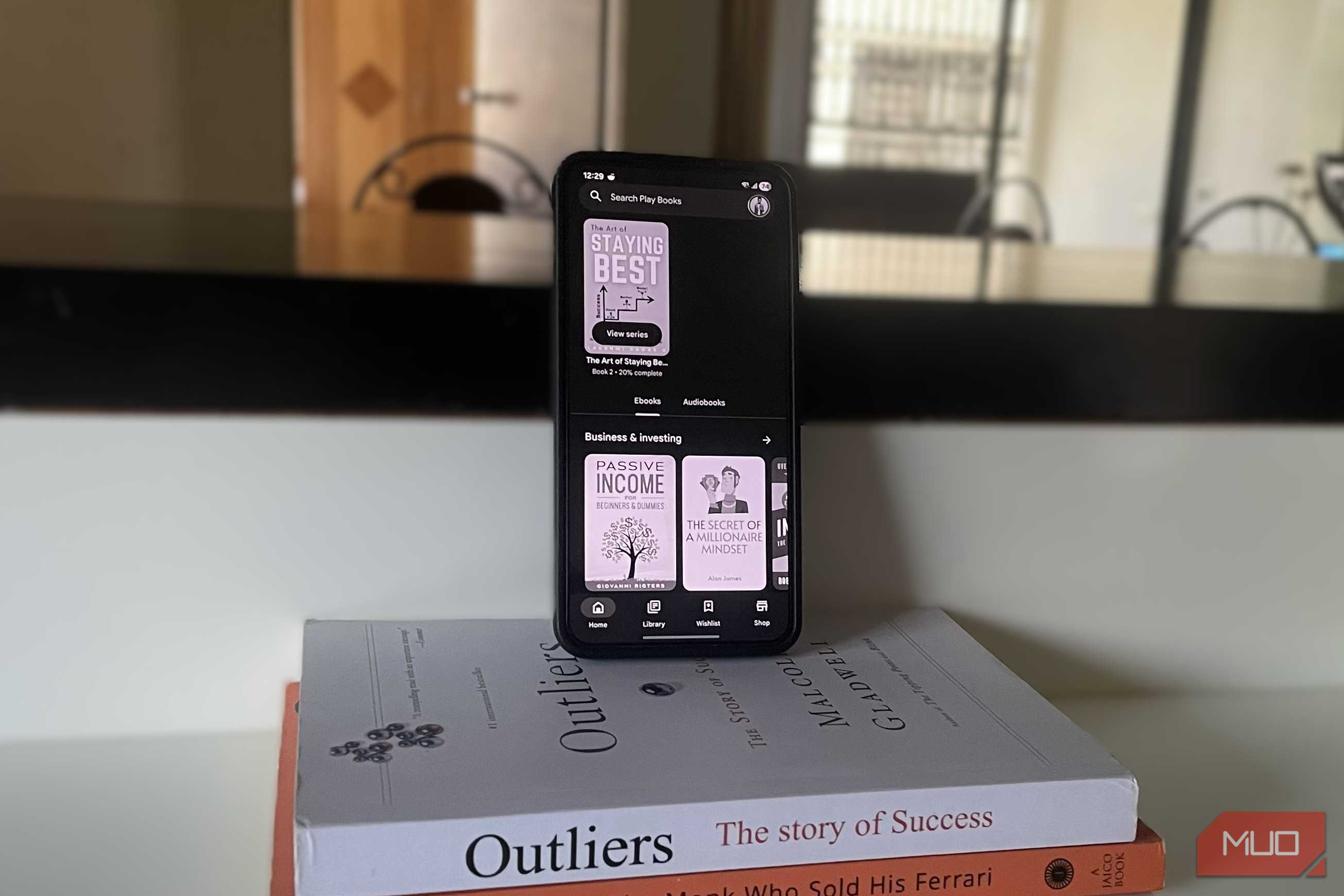 گوشی اندروید روی انبوهی از کتابها که eBook را نشان میدهد